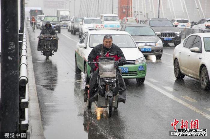  11月13日，吉林迎来入冬以来的首场降雪，市民冒雪出行。图片来源：视觉中国