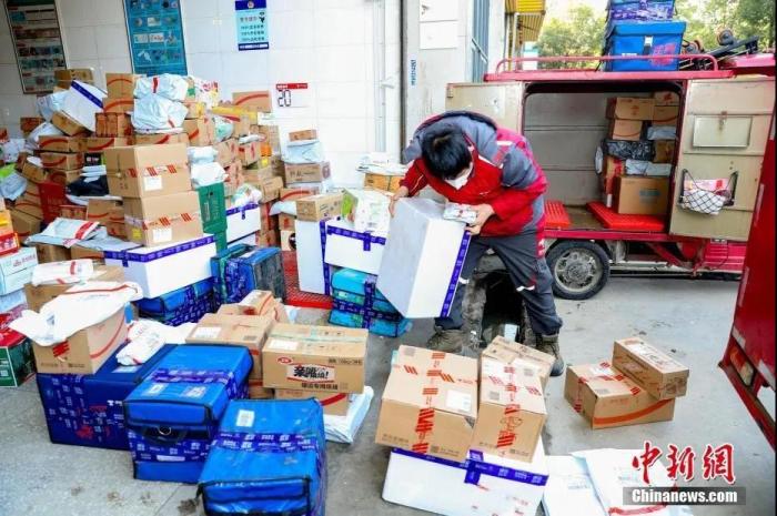 2月9日,武汉汉口将军路一家快递公司的快递点,快递员们整理到站的快件。新冠肺炎疫情之下,大批民众选择线上购物,快递员比往常更忙碌。中新社记者 张畅 摄