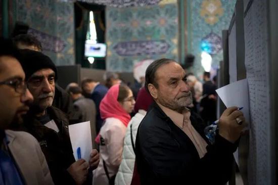 2月21日，在伊朗首都德黑兰，人们在一处投票站参加议会选举投票。
