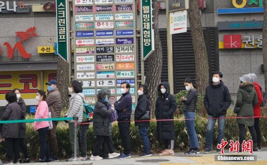 图为3月1日，在首尔钟路区一家超市外，民众排起长队等待购买口罩。中新社记者 曾鼐 摄