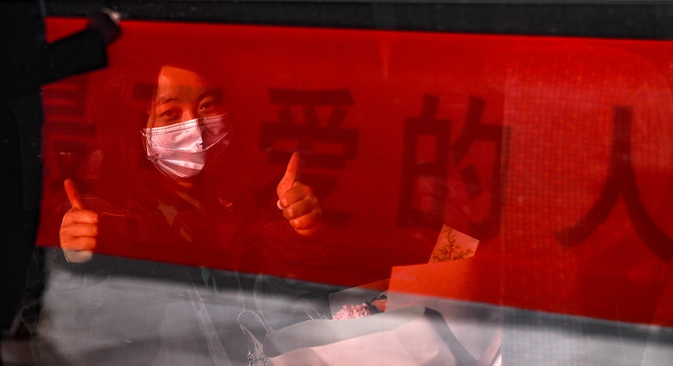 3月17日,在武汉火车站,一名坐上高铁列车即将离开武汉的南华大学附属第一医院医务人员向窗外的欢送人群竖起大拇指。新华社记者 沈伯韩 图