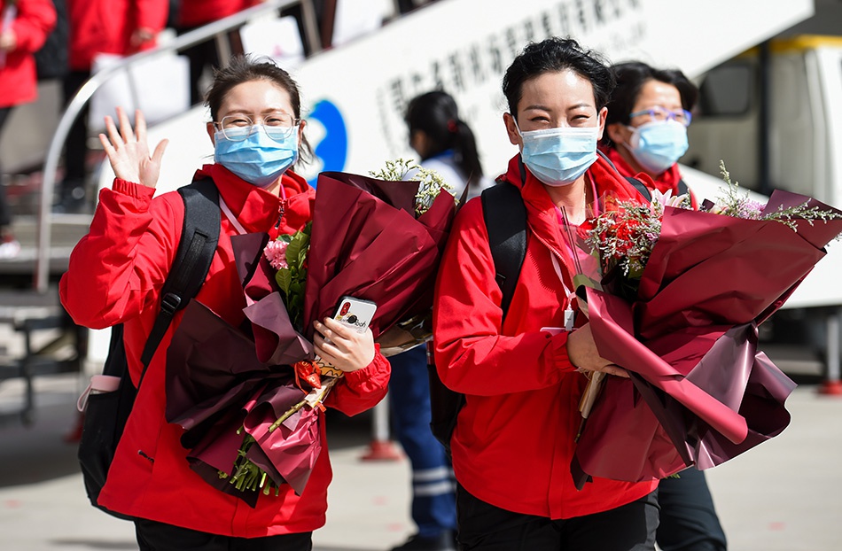 3月18日，在鄂尔多斯伊金霍洛国际机场，内蒙古援鄂医疗队队员向接机人员挥手致意。新华社记者 连振 图