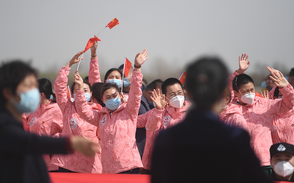3月18日,在河北石家庄正定国际机场,河北省援鄂医疗队队员向接机人员挥手致意。新华社记者 朱旭东 图