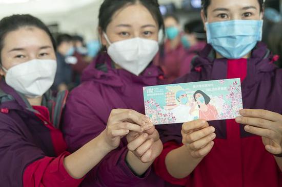 3月17日，在武汉天河机场，三名国家紧急医学救援队队员展示武汉天河机场纪念版登机牌。 （新华社）