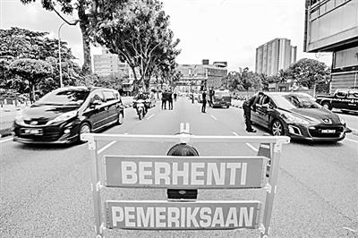 3月19日，在马来西亚吉隆坡，警察设卡检查来往车辆。马来西亚18日起在全国范围内采取为期两周的严格限制措施，禁止民众在非必要情况下外出。新华社发