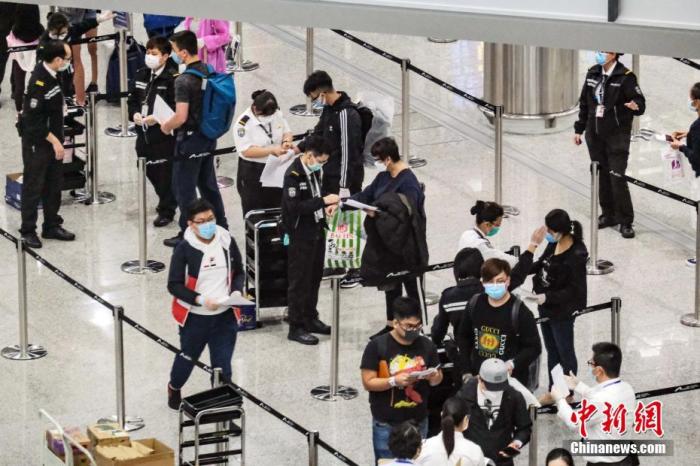资料图为香港特区政府人员在机场禁区，为从各地到港人士戴上手带作强制检疫监察之用。中新社记者 秦楼月 摄