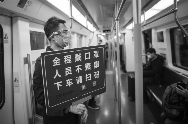  3月28日开始，武汉轨道交通部分线路恢复运营。当日，一名“随车安全员”在武汉地铁里引导服务乘客。（肖艺九 摄）