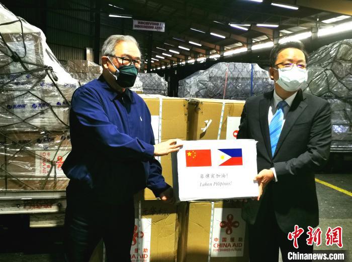 2020年3月21日，中国援助菲律宾物资抵达马尼拉。中国驻菲大使黄溪连(右)在马尼拉国际机场向菲律宾外交部长洛钦(左)交接物资。　关向东 摄