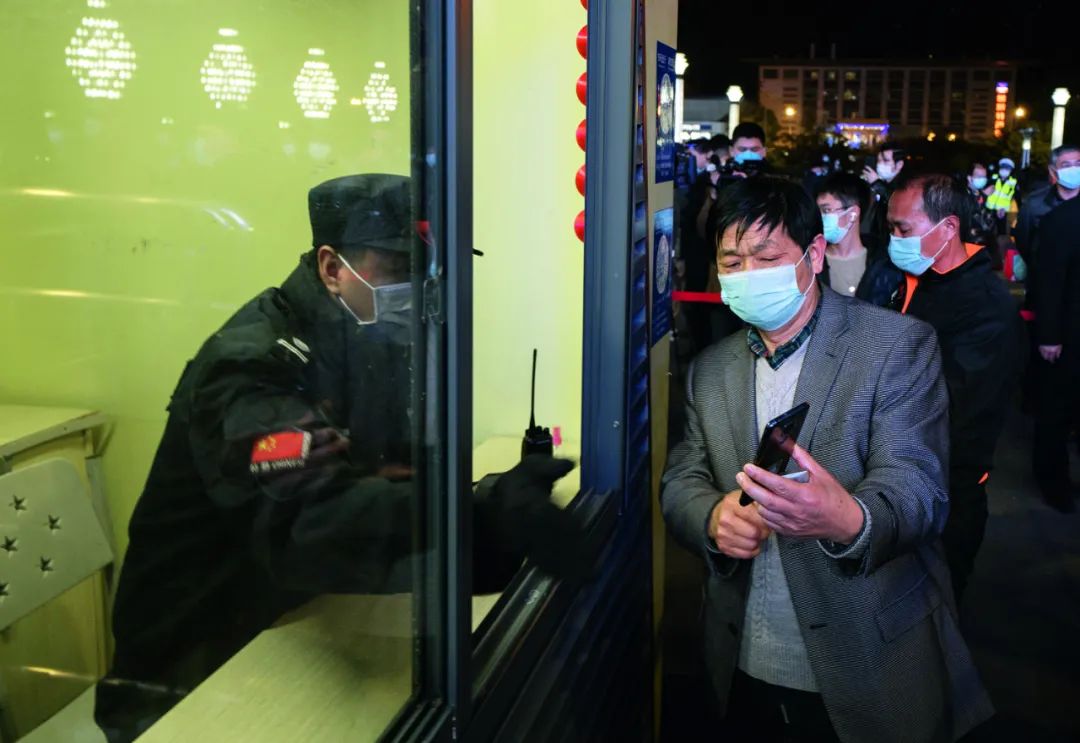 4月7日晚，旅客在武昌火车站向工作人员出示健康码。图/新华