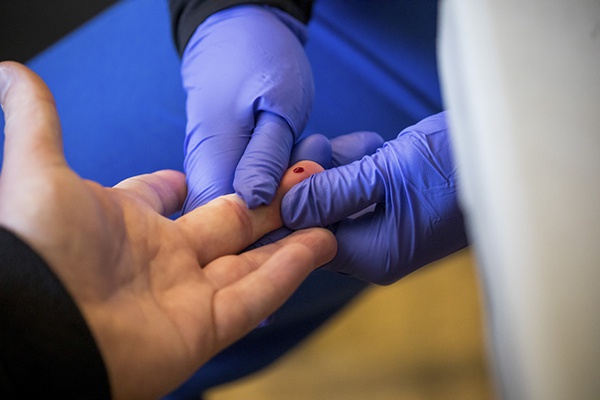  4月25日，在美国纽约布鲁克林区一家超市内的新冠抗体检测点，工作人员采集被测者血样。新华社 图