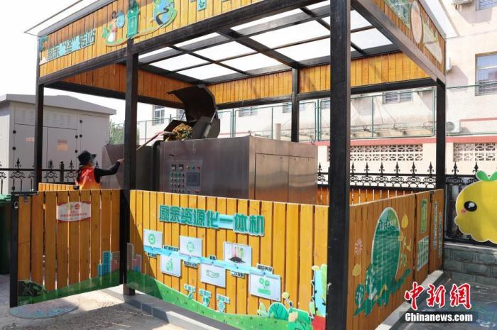 4月27日，在北京市海淀区二里庄社区，垃圾分类志愿者将厨余垃圾倒入厨余资源化一体机内。 中新社记者 蒋启明 摄