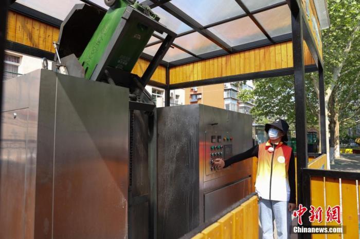 4月27日，在北京市海淀区二里庄社区，垃圾分类志愿者将厨余垃圾倒入厨余资源化一体机内。 中新社记者 蒋启明 摄