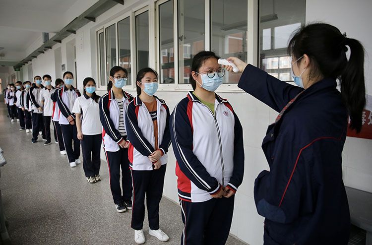 学生排队接受测温,体温正常才能进入教室。