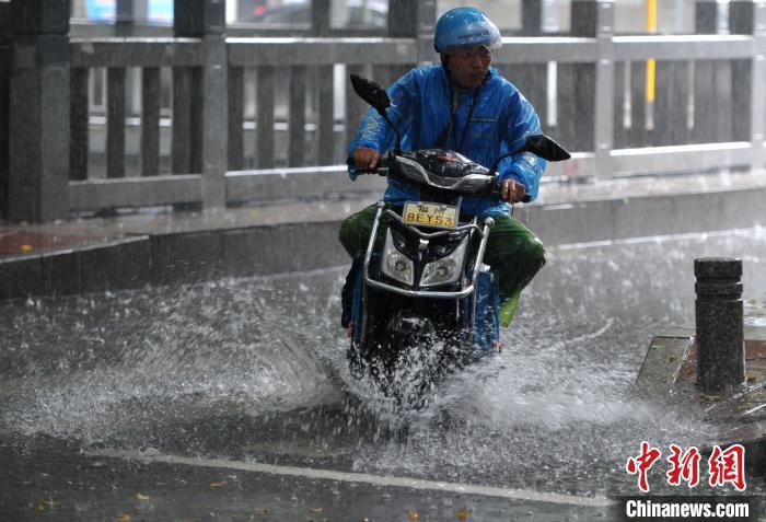 6月2日,福州外卖骑手经过积水路面。 张斌 摄