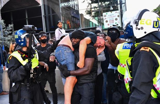 伦敦白人示威者被打得满脸鲜血，对立团体的黑人将其背到安全区域