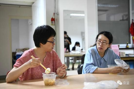 杨会娟(左)与同事曹丽娜一边吃早饭一边讨论工作