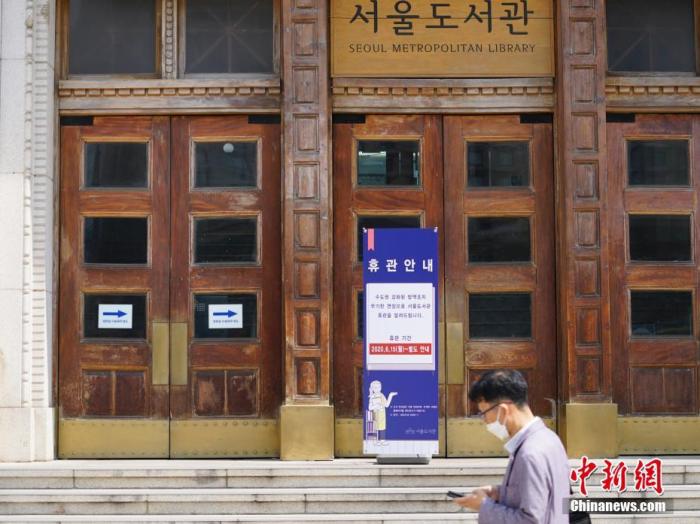 6月23日，一位韩国首尔市民经过首尔市立图书馆门前，该图书馆贴出闭馆通知。近来，包括韩国首尔、仁川、京畿道在内的首都圈确诊病例持续增加。 中新社记者 曾鼐 摄
