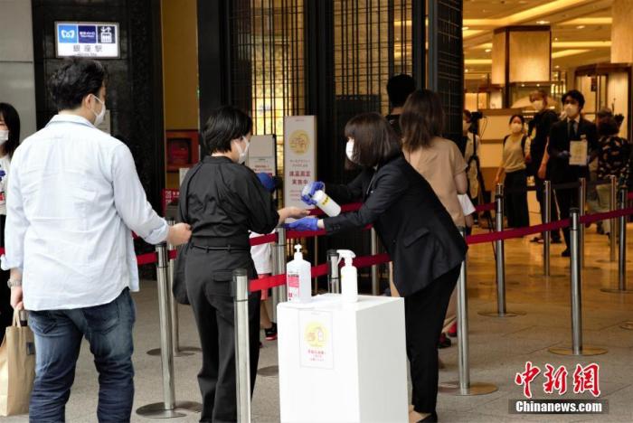 当地时间6月6日,日本东京都发布新冠肺炎疫情“东京警报”后的首个周末,虽然当地已进入疫情恢复阶段,但各商场仍采取多种防疫措施严阵以待。图为东京某商场为进店顾客进行消毒。 中新社记者 吕少威 摄