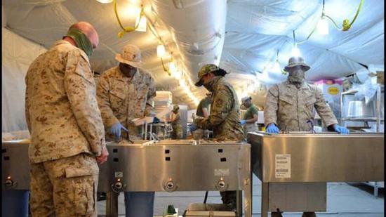 美军士兵在贾贝尔空军基地戴口罩进入食堂就餐