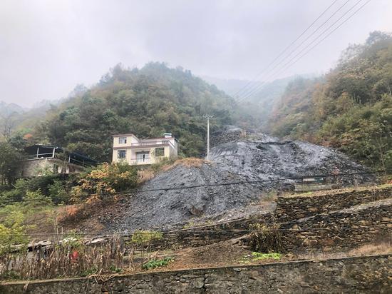 白河县凤凰村一户建在矿渣旁边的新房。