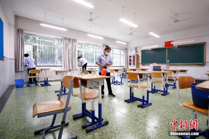 图为7月3日北京十二中保洁人员对考场及走廊进行清扫、消毒。 中新社记者 富田 摄