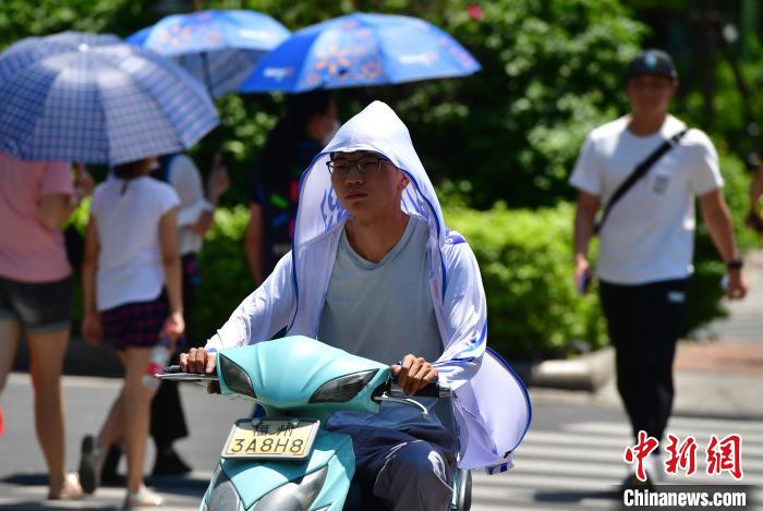 图为福州市民在烈日下出行。　张斌 摄