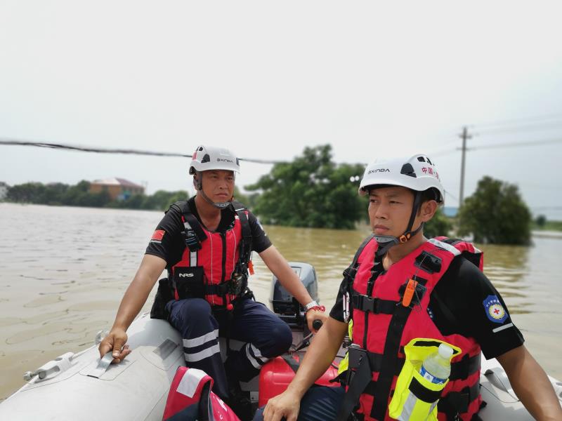 救援队在洪灾现场乘坐冲锋舟搜寻被困者。