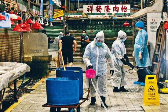 7月17日晚间,穿上防护服的相关人员在深水埗北河街街市进行清洁工作