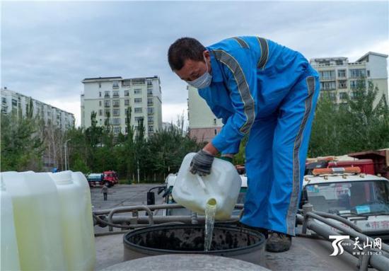 7月20日，乌鲁木齐市水磨沟区环卫清运队的工作人员正在往洒水车里添加消毒液。