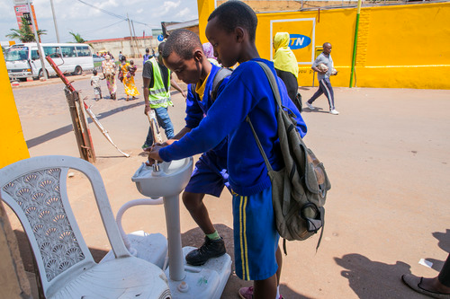 3月14日，在卢旺达首都基加利，儿童进入公交车站时洗手。新华社发