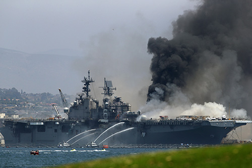  美军“好人理查德”号两栖攻击舰爆炸起火，消防艇喷水灭火。