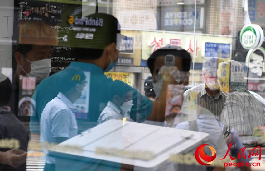 韩国首尔一餐厅工作人员正在为入店顾客进行体温测量。 裴埈基摄