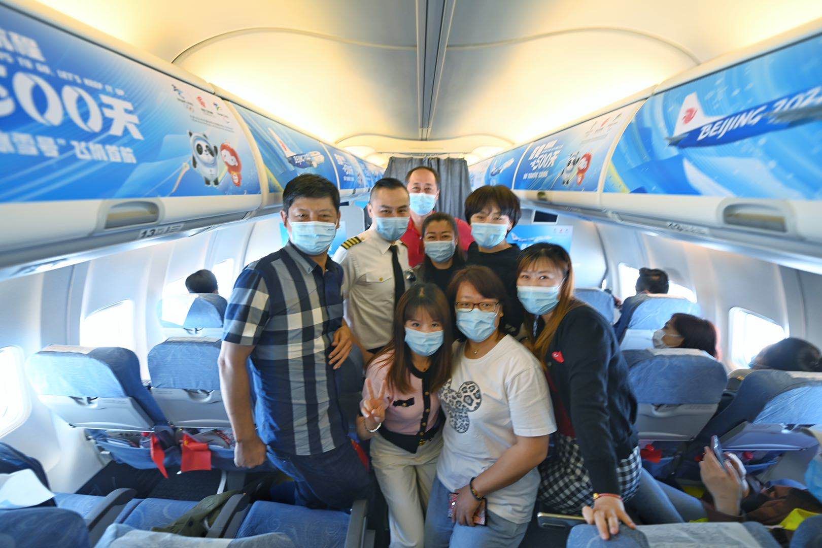  航班上举行了特殊的欢迎活动，旅客们与机组人员合影。新京报记者 陶冉 摄