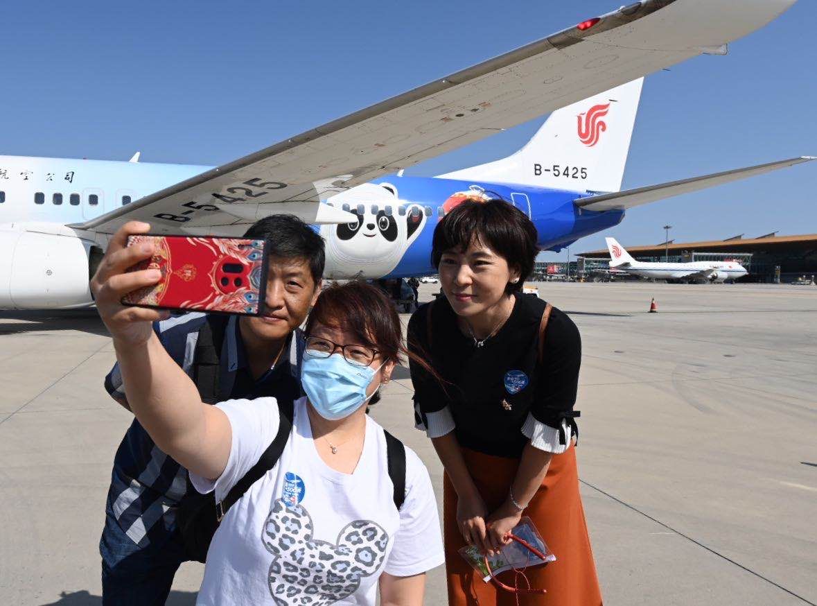 “冬奥冰雪号”航班的旅客拍照合影。 新京报记者 陶冉 摄