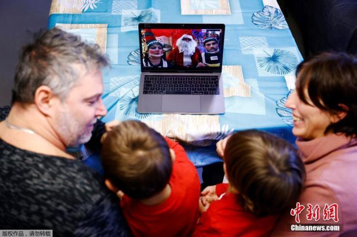 资料图：当地时间12月8日，在意大利罗马，一个装扮成圣诞老人的男子通过网络直播跟孩子们互动。