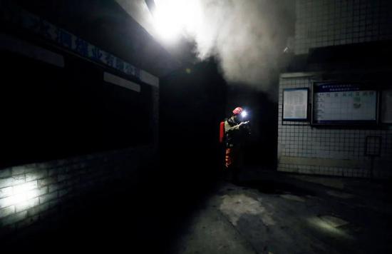 12月4日晚，在重庆市永川区吊水洞煤矿，救援人员准备前往煤矿井口处测量烟雾中一氧化碳浓度。图/新华社