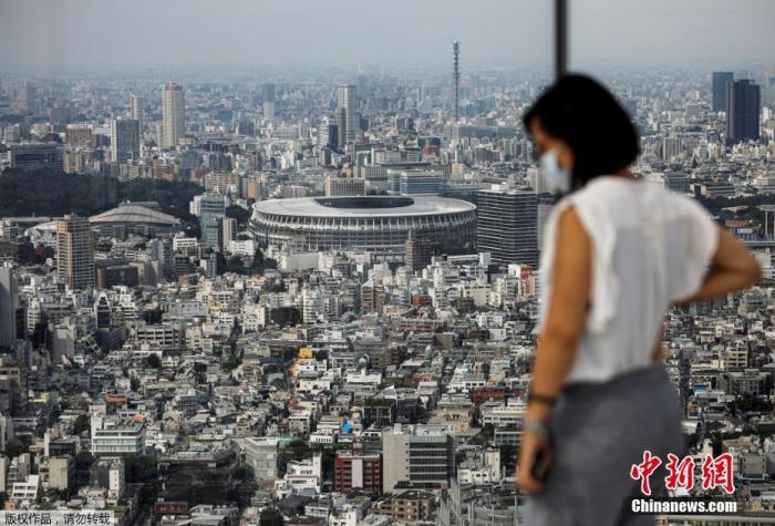 资料图:日本东京一处观景台上,一名戴口罩的游客远眺日本东京奥运会和残奥会的主体育场。Issei Kato