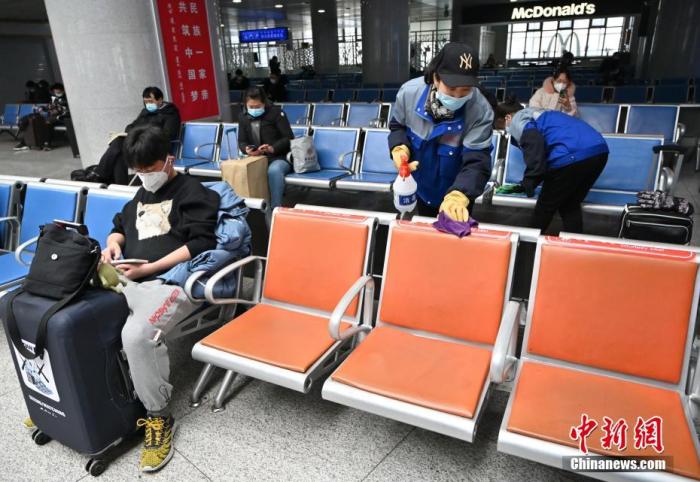 1月25日,呼和浩特火车站,工作人员在候车室内对座椅消毒。 中新社记者 刘文华 摄