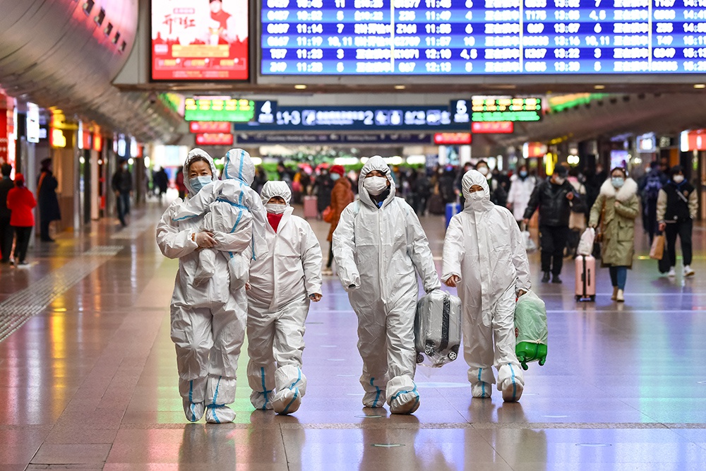 2021年1月28日，北京西站，身着防护服的一家人在候车室内寻找候车区域。刘帅冶/人民视觉 图