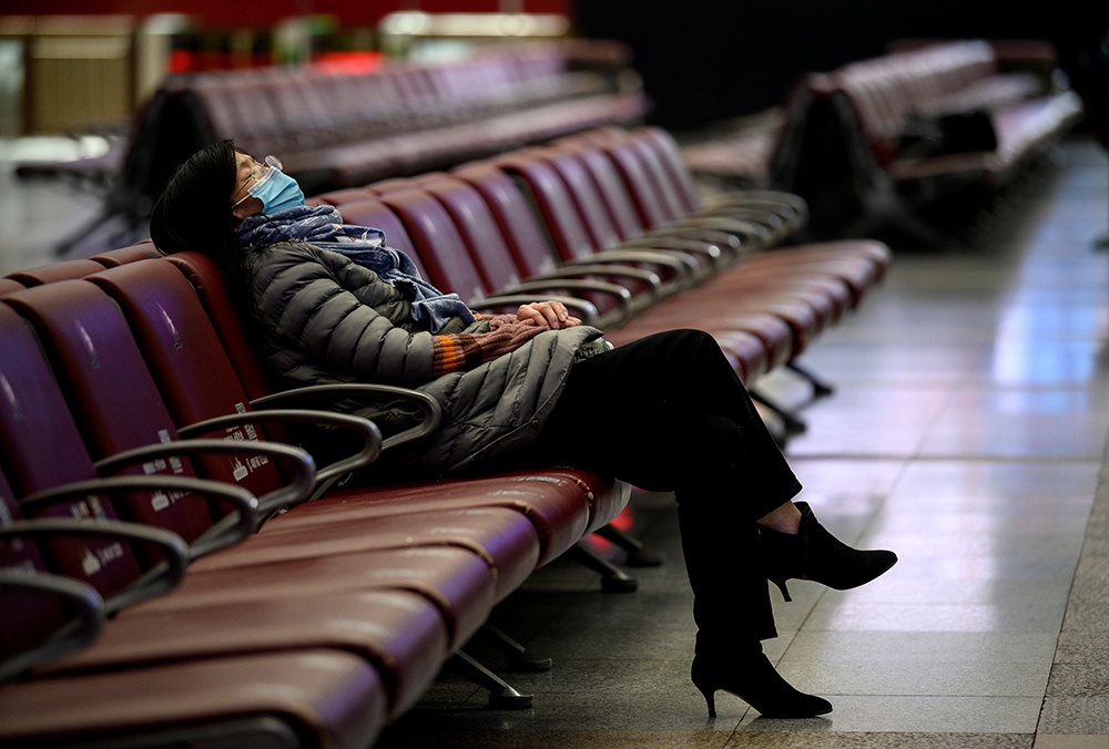 2021年1月28日，春运首日，北京，一名女士在空旷的火车站候车室内闭目休息。当日，全国铁路预计发送旅客400万人次，同比下降66%。人民视觉 图