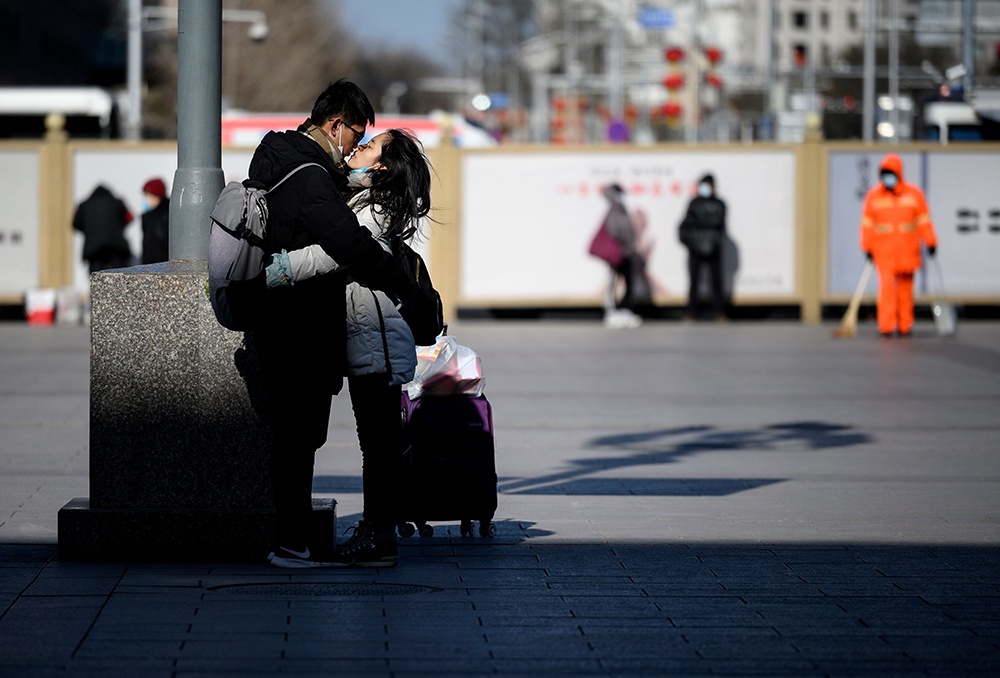 2021年1月28日，北京，一对情侣在北京火车站外拥吻。今年春运不同于以往，我国本土疫情多点零星散发和局部聚集性疫情交织叠加，多地出台了减少人员流动的引导或限制性措施。全国铁路春运客流将下调至2.96亿人次。人民视觉 图