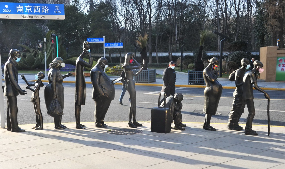 2021年1月29日，上海，眼下防控新冠疫情正处于关键时刻，戴口罩成了个人防疫举措之一。在延安西路、南京西路上，一组“街头候车”的雕塑人物也都戴上了口罩，虽然只是行为艺术，但也由此提醒大家，出门戴口罩，这一防疫举措人人都必须做到。杨建正/人民视觉 图