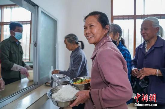 资料图：2月23日，广西隆安县东信村“爸妈食堂”内，老人们排队取餐。中新社记者 陈冠言 摄