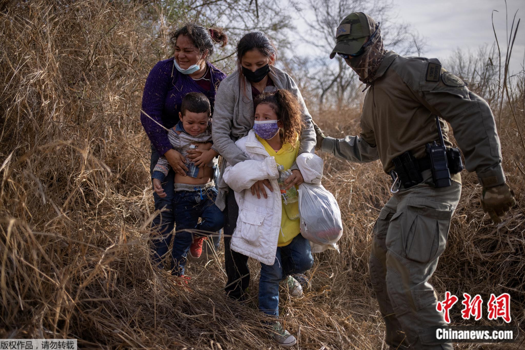 在美国得州里奥格兰德，边境执法者要求躲在灌木丛中的非法移民家庭走出来，以便将他们戴上手铐逮捕并转移。