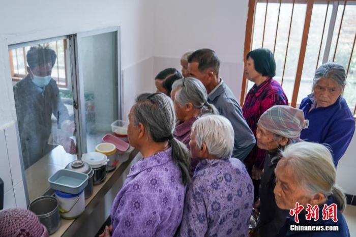 资料图：广西隆安县东信村“爸妈食堂”内，老人们排队取餐。 中新社记者 陈冠言 摄