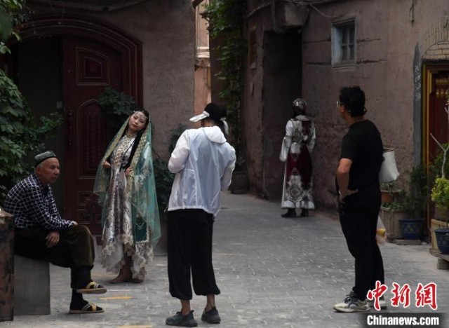 图为旅拍店工作人员在喀什古城里为游客进行拍摄。　孙亭文 摄